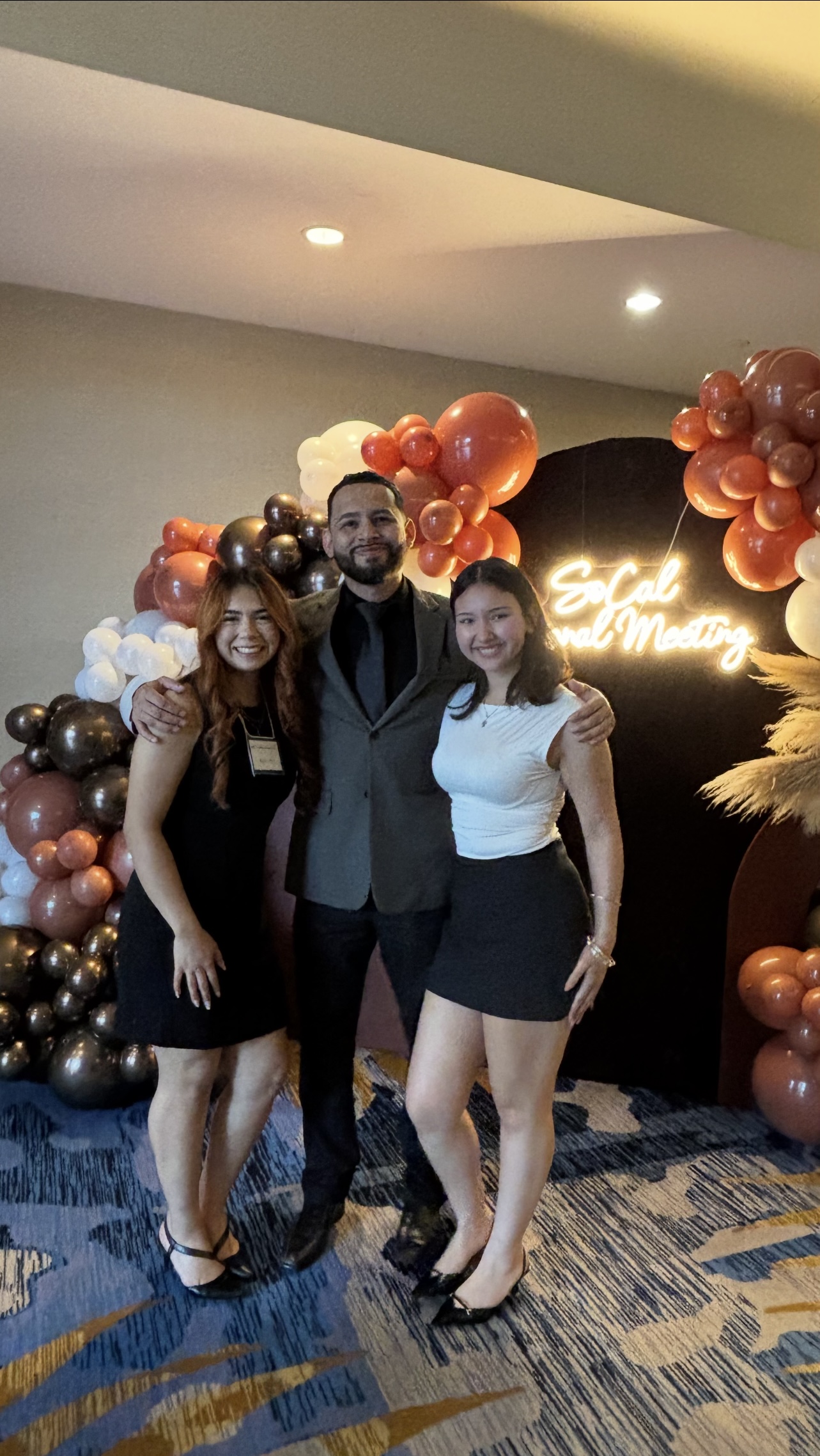 Infinite Reign Solution team at the SoCal Regional Meeting with festive orange and gold backdrop